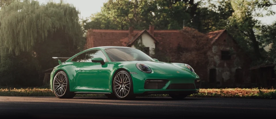 Grüner Porsche 911 Carrera 4S seitlich vor altem Gebäude